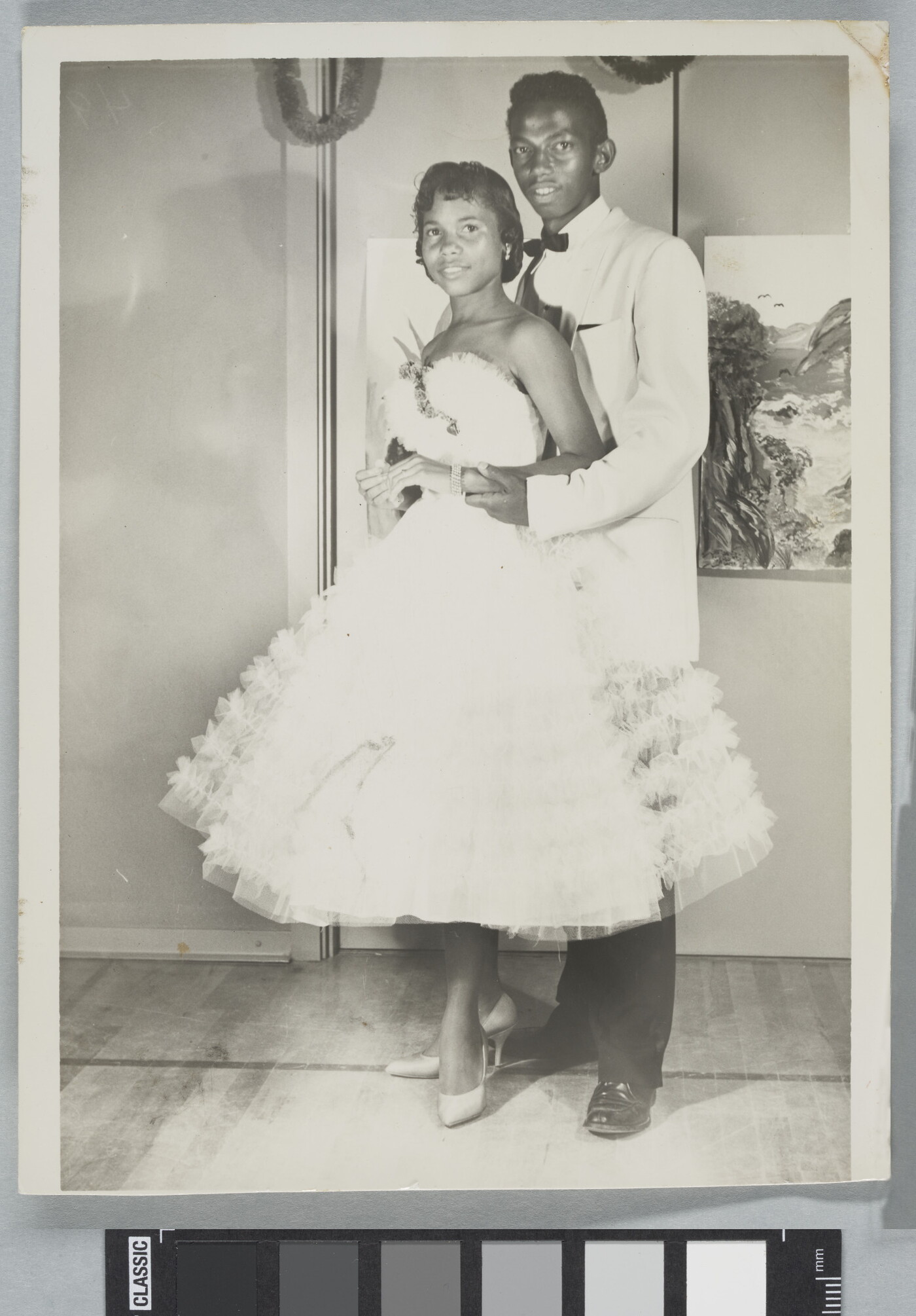 A black-and-white photograph of a Black couple in formal dress at a dance.