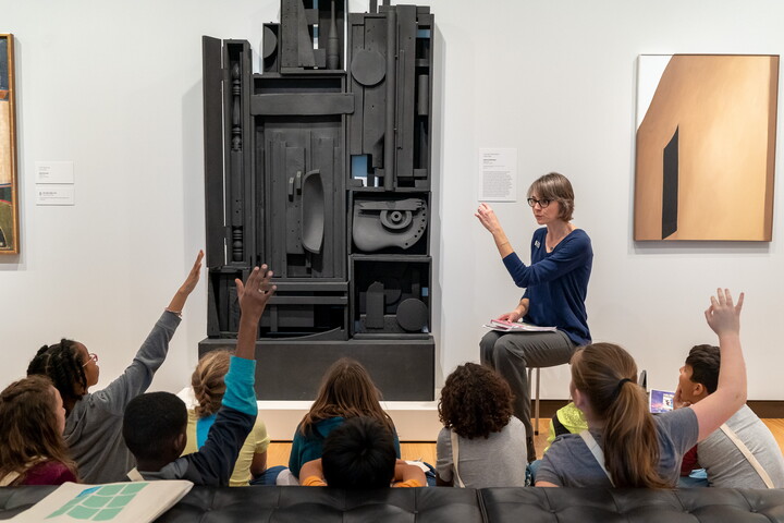 Students at the Carter sit on a gallery floor in front of a Gallery Teacher.