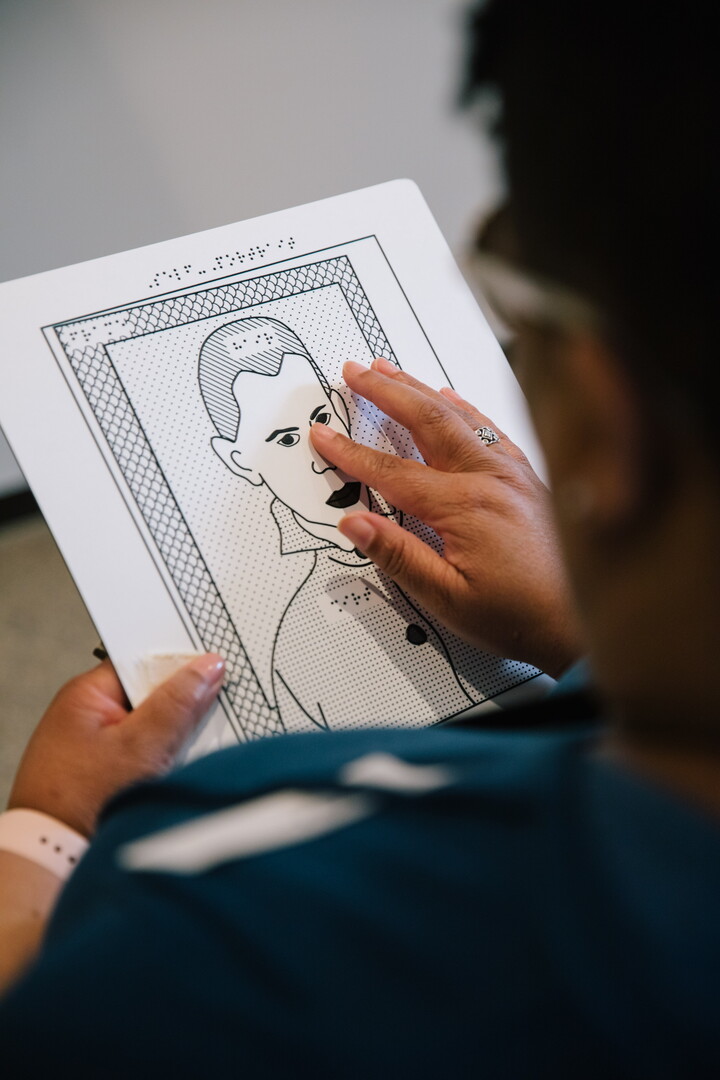 A visitor runs their hand over a raised line drawing.