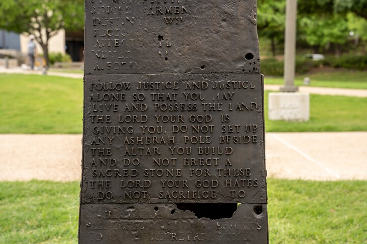 A detail of a bronze obelisk with fragments of text covering each side.