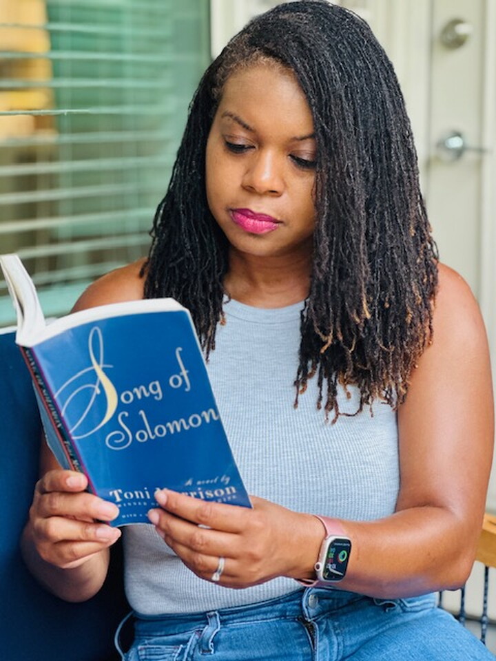 A woman reads a paperback copy of "Song of Solomon."