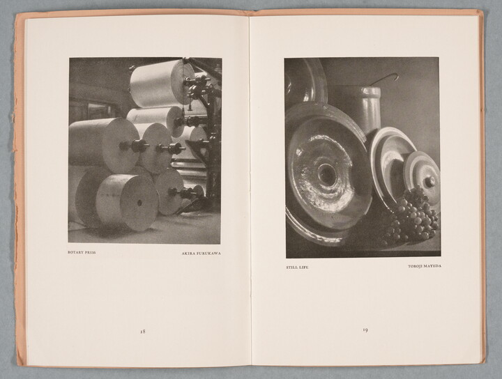 An open book showing a spread: on the left, a black-and-white photograph of cylinders of a printing press; on the right as still life of metal discs and grapes.