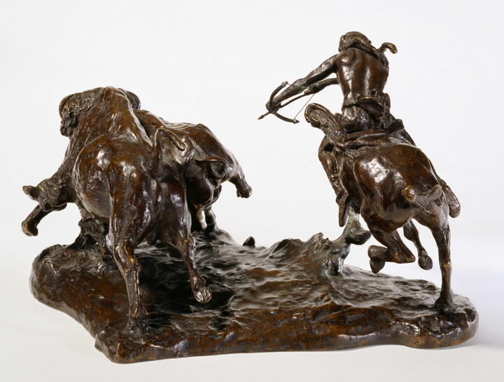 A bronze sculpture of a Native American on horseback hunting bison with a bow and arrow.