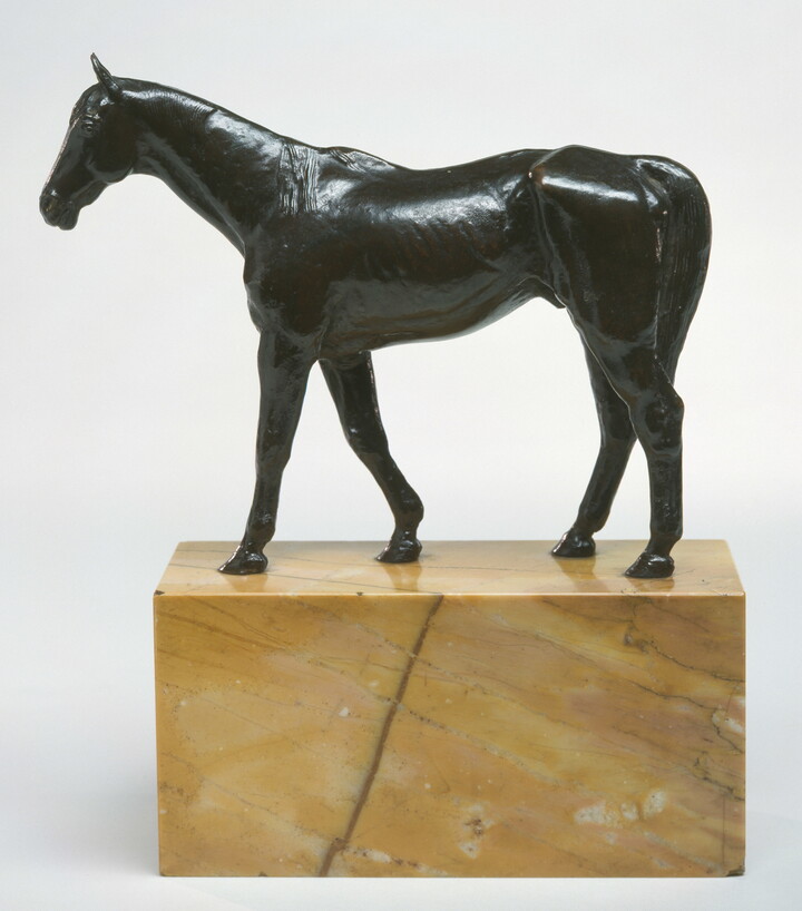 A bronze sculpture of a muscular horse with a long tail on a base of yellow marble.