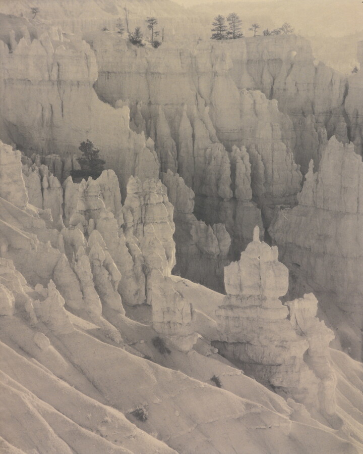 A sepia-toned photograph of rock spires as viewed from high up.