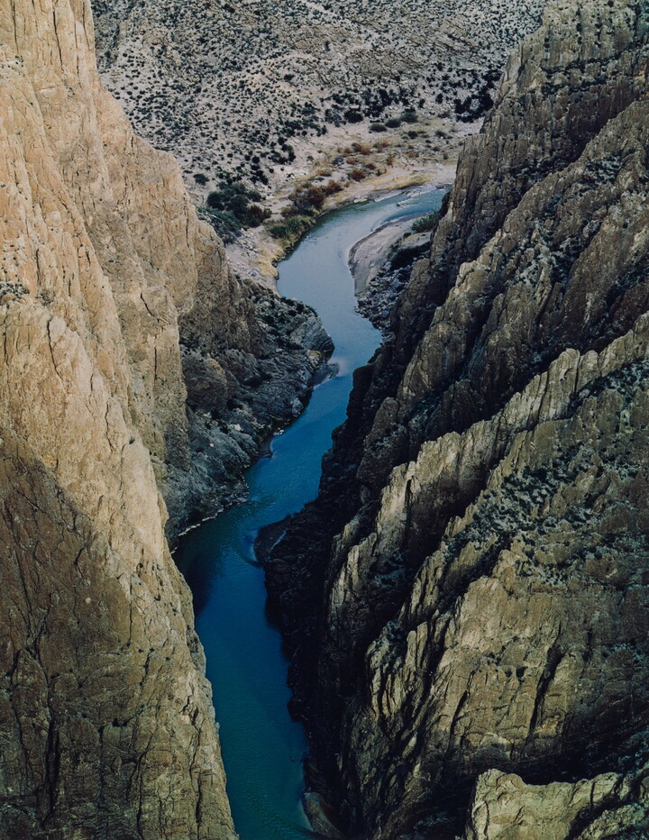 A color photograph taken from above of a river running through a narrow and steep canyon.