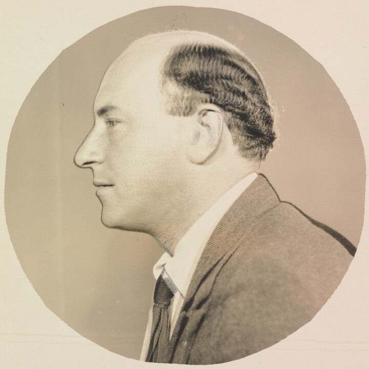 A circular black-and-white photograph of a balding White man in profile.