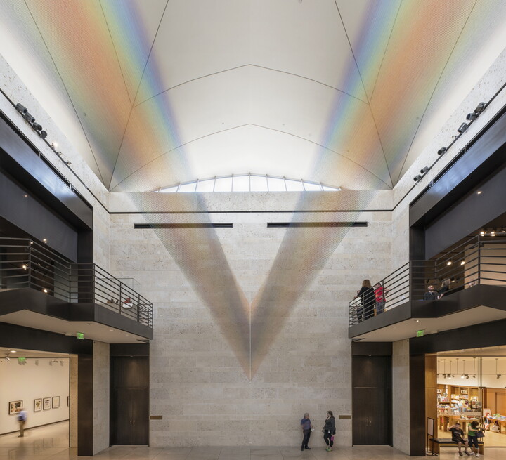 A large installation of multicolored sewing thread that stretches from one wall to the ceiling in the Carter&#039;s Atrium and looks like a rainbow.