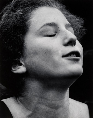 Black and white photo of a pre-teen holding her head to the sky; her eyes are closed