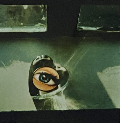 An abstract color photograph of a glass heart with a photo or painting of a blue eye in the center.