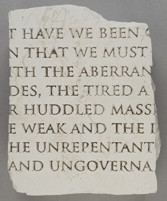 A broken slab of marble with words carved into it.