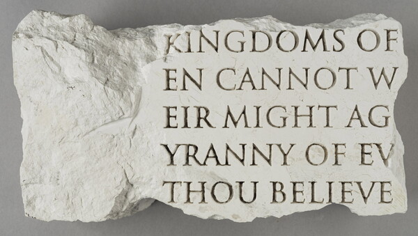 A broken slab of marble with words carved into it.