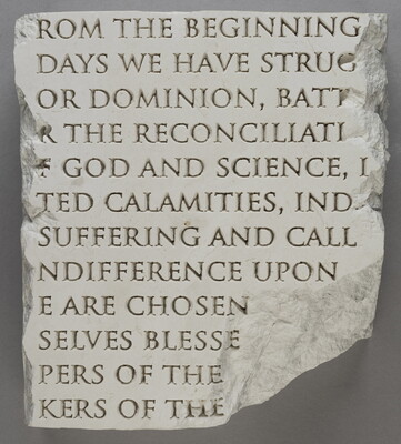 A broken slab of marble with words carved into it.