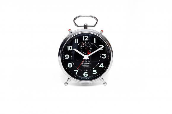 A silver and black analog alarm clock with the time at 10:10.