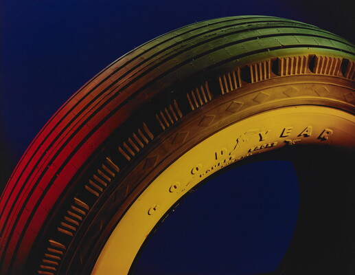 A color photograph of a close-up of the tread on a Goodyear tire, all lit with a yellow-ish light.