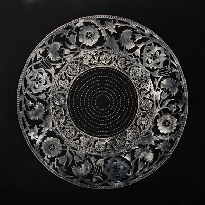A detailed circular floral design in silver with circles stitched in the center on a black background.