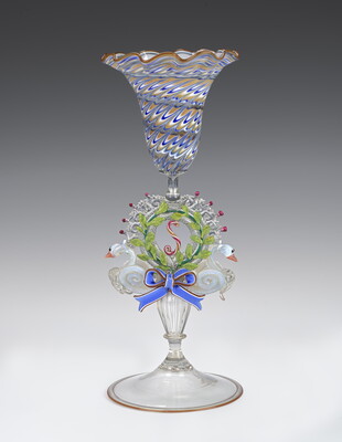 A glass goblet with lots of colored decoration including two swans making up the decorative stem.
