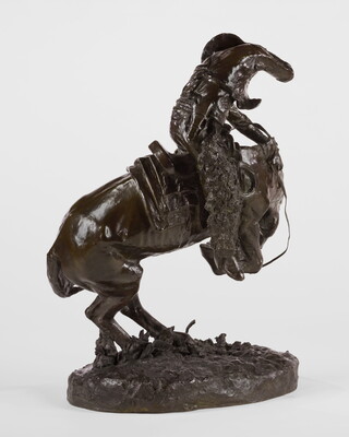 A sculpture of a man riding a bucking horse around a rattlesnake.