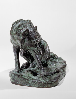 A bronze sculpture of a wolf crouching on its haunches.