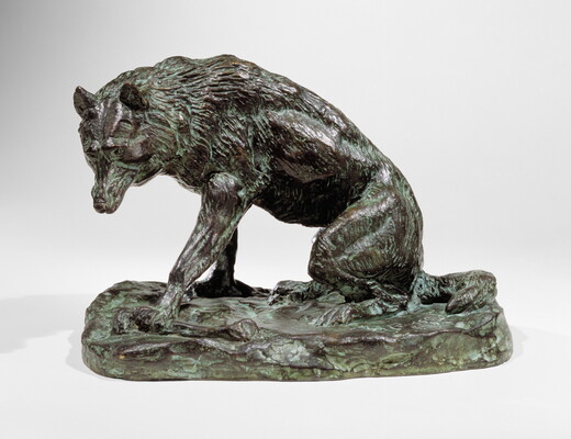 A bronze sculpture of a wolf crouching on its haunches.