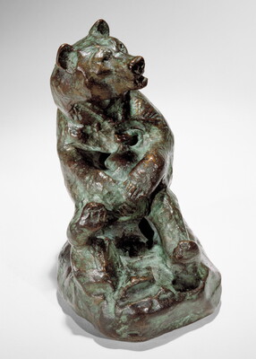 A bronze sculpture of a sitting bear holding a jug in its paws.