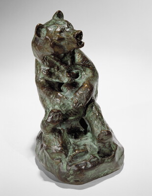 A bronze sculpture of a sitting bear holding a jug in its paws.