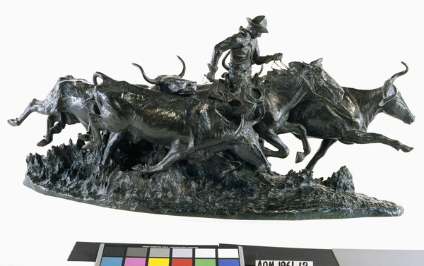 A bronze sculpture of a cowboy on a running horse surrounded by stampeding cattle.