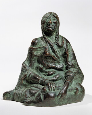 A bronze sculpture of a seated Native American person wrapped in a robe.