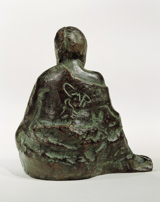 A bronze sculpture of a seated Native American person wrapped in a robe.