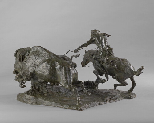 A sculpture of a Native American on horseback using a bow and arrow to hunt two bison.
