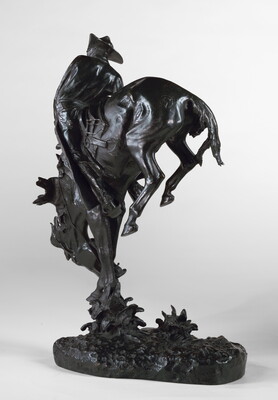 A bronze sculpture of a cowboy hanging onto a bucking bronco.
