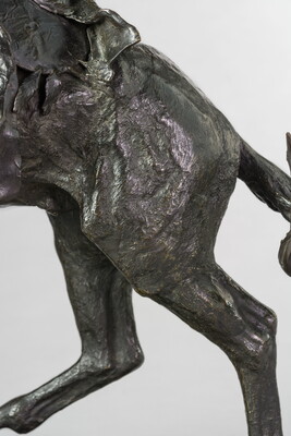 A detail of a bronze sculpture showing the rear of the horse of a man on horseback holding a piece of scalp and hair in his hand thrusted above his head triumphantly.