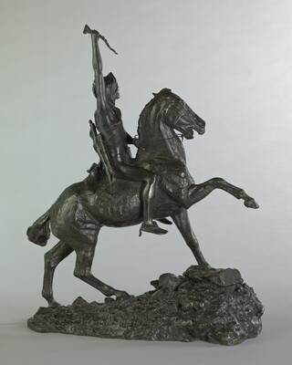 A bronze sculpture of a man on horseback holding a piece of scalp and hair in his hand thrusted above his head triumphantly.