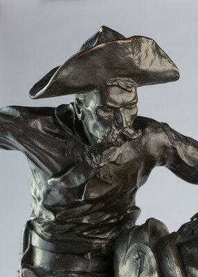 A bronze sculpture of a cowboy balancing on a rearing horse.