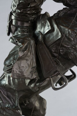 A bronze sculpture of a cowboy balancing on a rearing horse.