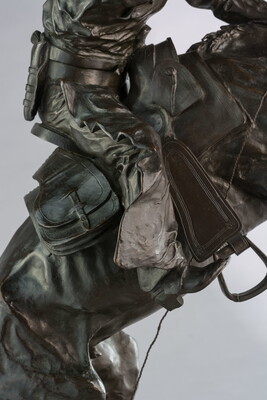 A bronze sculpture of a cowboy balancing on a rearing horse.