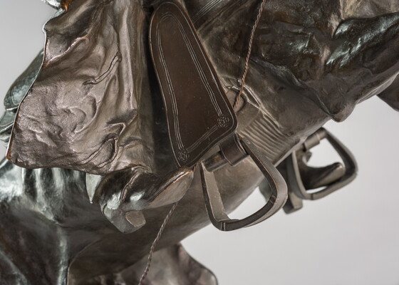 A bronze sculpture of a cowboy balancing on a rearing horse.