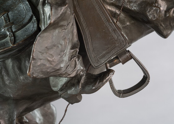 A bronze sculpture of a cowboy balancing on a rearing horse.