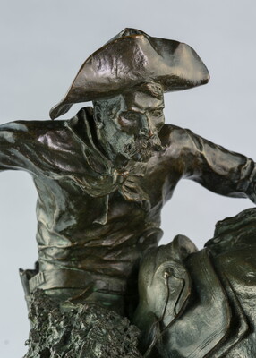 A detail of bronze sculpture of a cowboy balancing on a rearing horse.