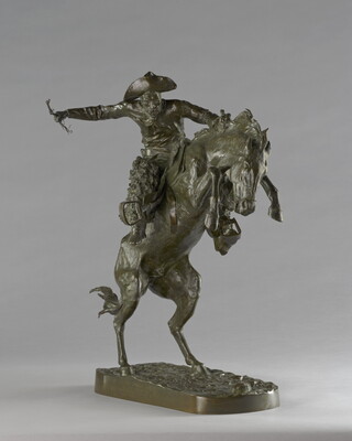 A bronze sculpture of a cowboy balancing on a rearing horse.