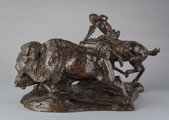 A bronze sculpture of a Native American on horseback hunting bison with a bow and arrow.