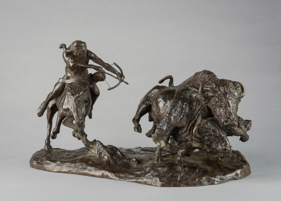 A bronze sculpture of a Native American on horseback hunting bison with a bow and arrow.