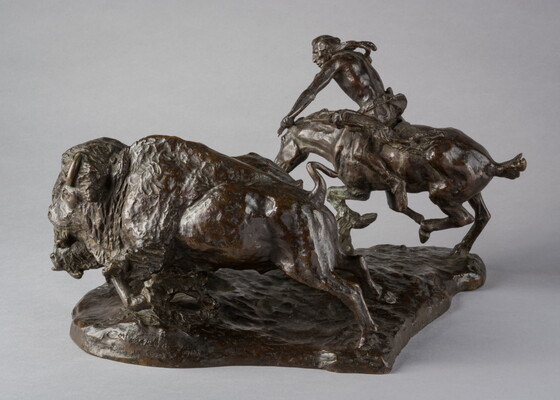 A bronze sculpture of a Native American on horseback hunting bison with a bow and arrow.