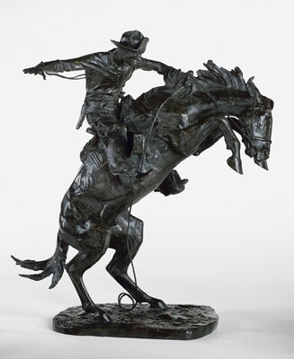 A bronze sculpture of a cowboy balancing on a rearing horse.
