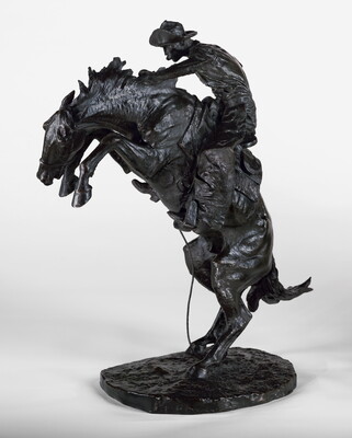 A bronze sculpture of a cowboy balancing on a rearing horse.