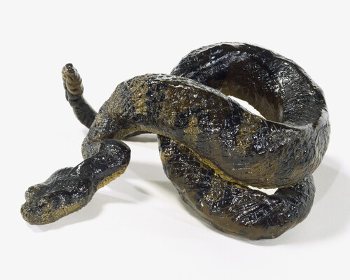 A painted sculpture of a coiled, multicolored rattlesnake.