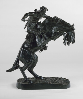 A bronze sculpture of a cowboy balancing on a rearing horse.