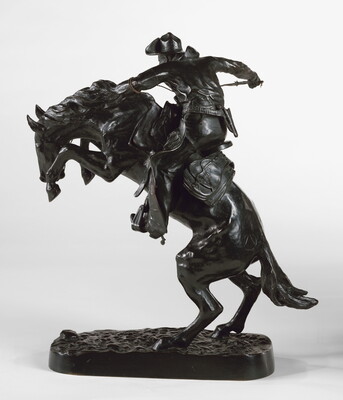 A bronze sculpture of a cowboy balancing on a rearing horse.