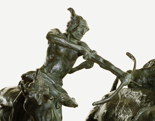 A detail of a bronze sculpture of two Native men, one with a spear and the other with a bow, on horseback circling a group of bison.