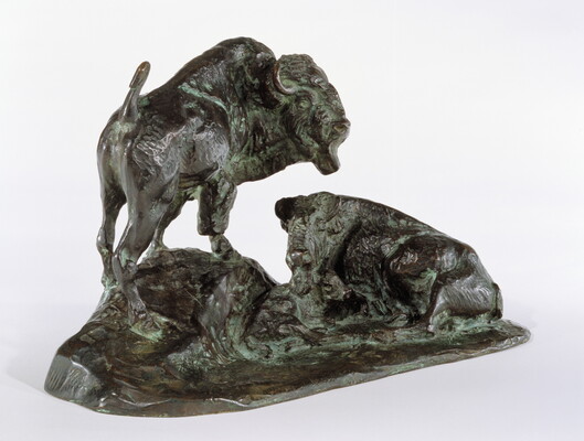 A bronze sculpture of two bison, one lying down and the other standing.